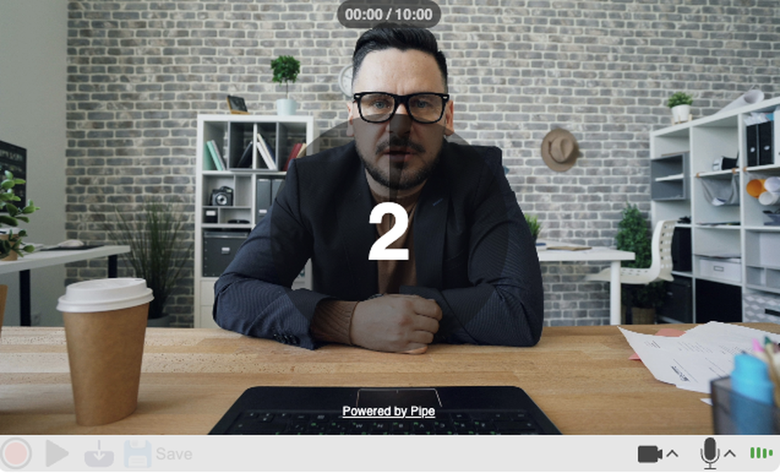 A man is starting to recording himself using addpipe's recording client, and is waiting for the countdown timer displayed in the middle of the recording client to end in order for the recording to start
